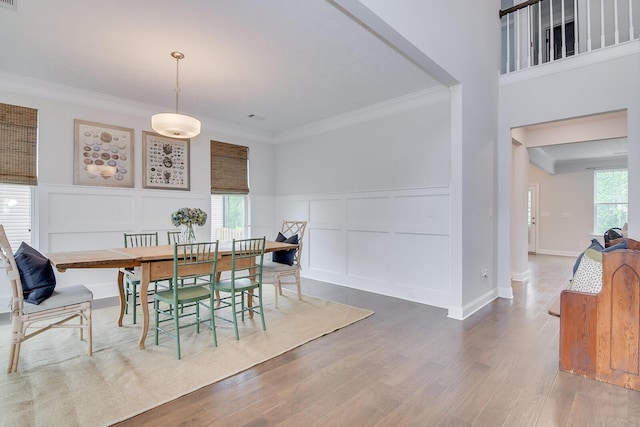 dining room featuring a decorative wall, wood finished floors, ornamental molding, and a wainscoted wall