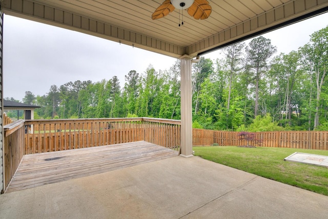 view of patio with ceiling fan, a deck, and view of scattered trees
