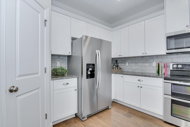 kitchen with appliances with stainless steel finishes, white cabinetry, crown molding, dark stone countertops, and decorative backsplash