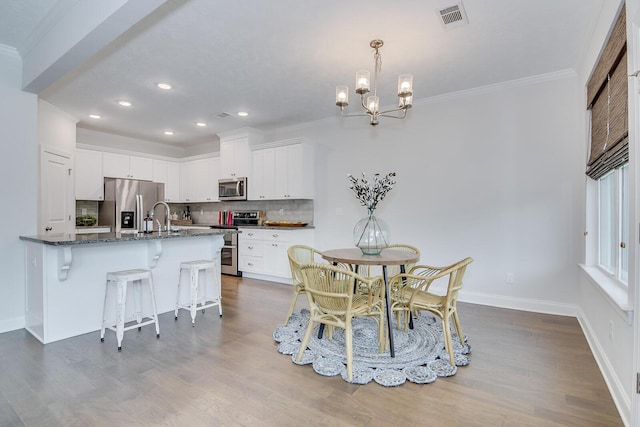 dining area with a chandelier, ornamental molding, dark wood-style floors, recessed lighting, and baseboards