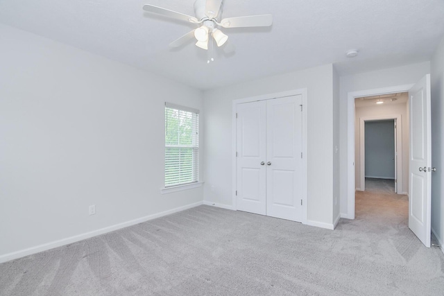 unfurnished bedroom featuring carpet, baseboards, a closet, and ceiling fan