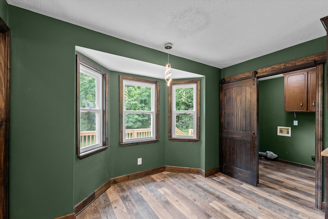 221 Creek View Cir, Martinez, GA 30907 - unfurnished dining area featuring a barn door, wood finished floors, and a textured ceiling