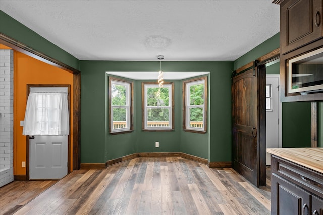 221 Creek View Cir, Martinez, GA 30907 - unfurnished dining area with a barn door, a textured ceiling, and light wood-type flooring