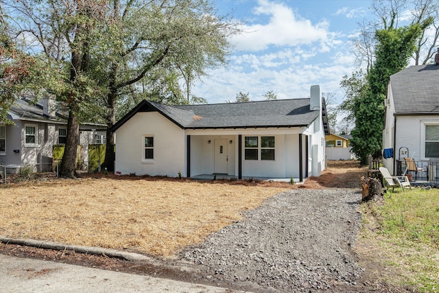 ranch-style house with roof with shingles, fence, and stucco siding