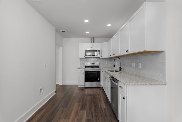 kitchen with dark wood finished floors, visible vents, decorative backsplash, appliances with stainless steel finishes, and light stone countertops