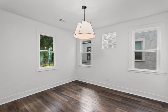 empty room featuring dark wood-style floors, plenty of natural light, and baseboards