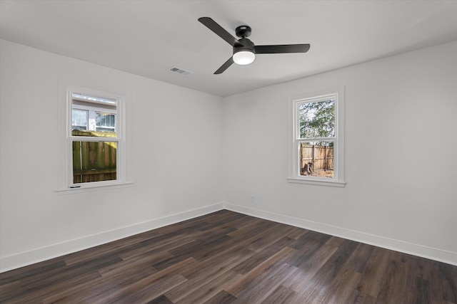 empty room featuring a ceiling fan, visible vents, baseboards, and dark wood-type flooring