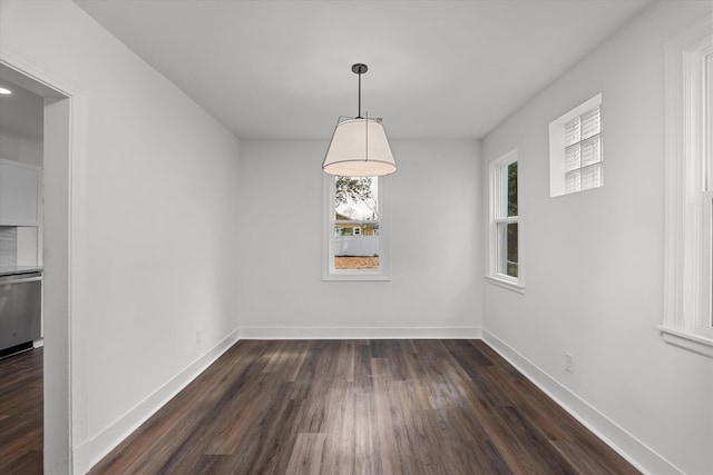 unfurnished dining area featuring dark wood-type flooring and baseboards