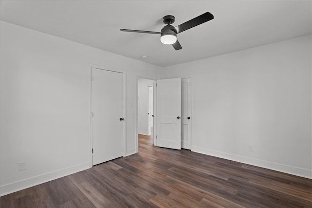 unfurnished bedroom with dark wood-type flooring, a ceiling fan, and baseboards