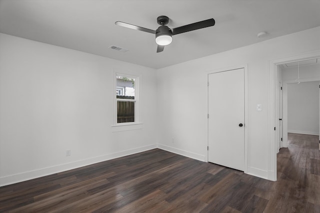 unfurnished bedroom featuring attic access, visible vents, baseboards, dark wood-style floors, and ceiling fan