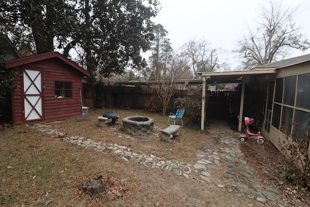 view of yard featuring an outdoor fire pit, a sunroom, and a storage shed