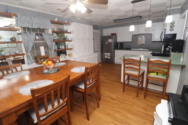 dining room with sink, light wood-type flooring, and ceiling fan