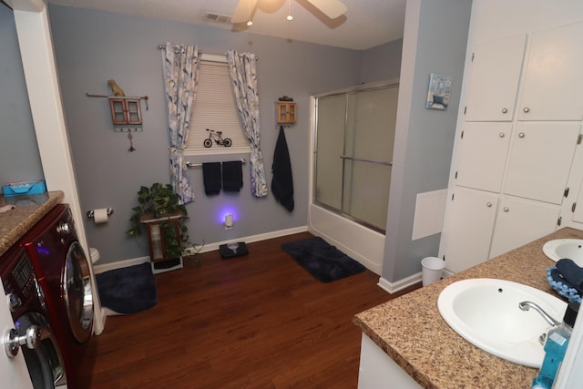 full bathroom featuring toilet, hardwood / wood-style flooring, bath / shower combo with glass door, washer / dryer, and vanity