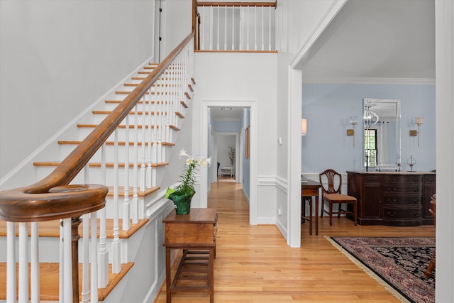 entrance foyer with ornamental molding, stairs, and wood finished floors