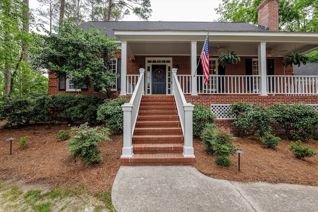 view of front of property featuring a chimney, a porch, and brick siding