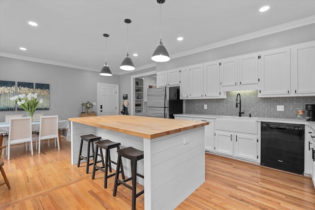kitchen with white cabinets, dishwasher, wood counters, freestanding refrigerator, and ornamental molding