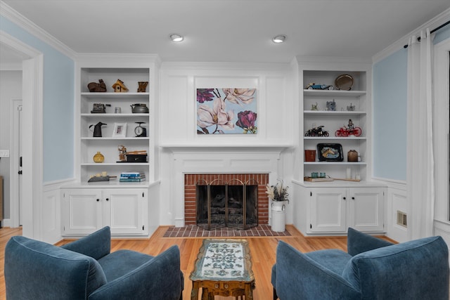 living area featuring crown molding, built in features, and light wood finished floors