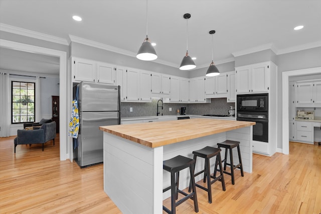 kitchen featuring backsplash, white cabinetry, wood counters, and black appliances