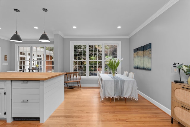 dining space with crown molding, baseboards, and light wood finished floors