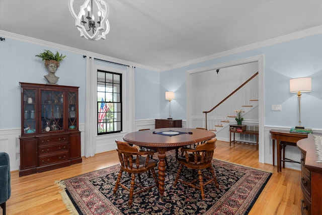 dining room featuring light wood-style floors, ornamental molding, a notable chandelier, and stairway