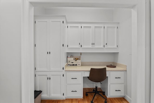 office space with built in desk and light wood-type flooring
