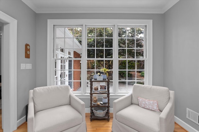 living area with ornamental molding, visible vents, plenty of natural light, and light wood-style flooring