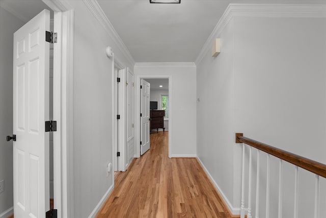 corridor featuring light wood-style floors, baseboards, and ornamental molding
