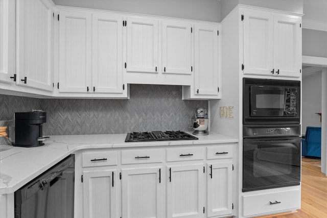 kitchen with backsplash, white cabinetry, light stone countertops, and black appliances