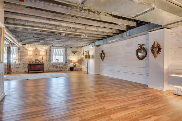 interior space with wooden walls, light hardwood / wood-style floors, and brick wall