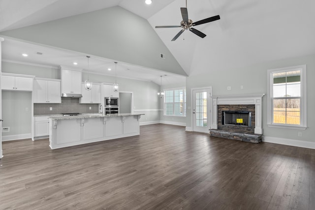 kitchen with decorative backsplash, appliances with stainless steel finishes, pendant lighting, white cabinetry, and an island with sink