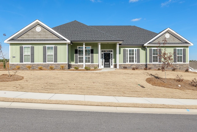 craftsman inspired home with stone siding, roof with shingles, and board and batten siding