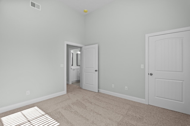 unfurnished bedroom with a towering ceiling and light carpet