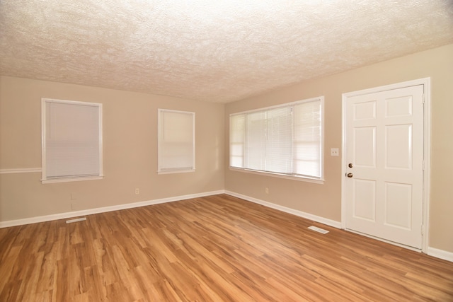 empty room featuring a textured ceiling and light hardwood / wood-style flooring