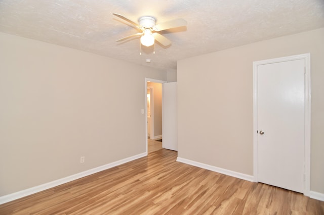 empty room with a textured ceiling, light hardwood / wood-style flooring, and ceiling fan