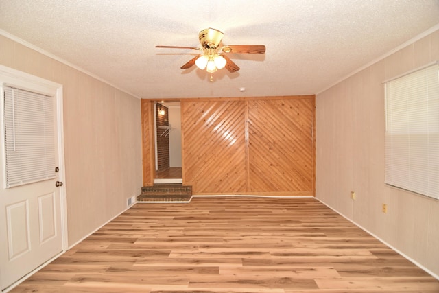 unfurnished room featuring a textured ceiling, ceiling fan, and wood walls