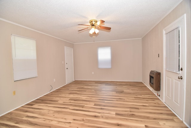 unfurnished living room featuring ceiling fan, ornamental molding, heating unit, a textured ceiling, and light wood-type flooring