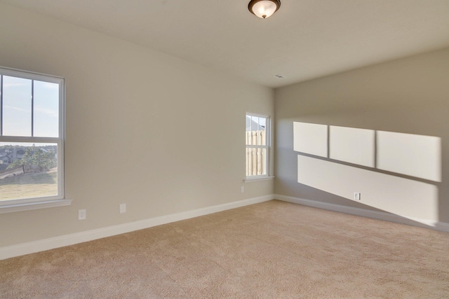 unfurnished room featuring light carpet and baseboards