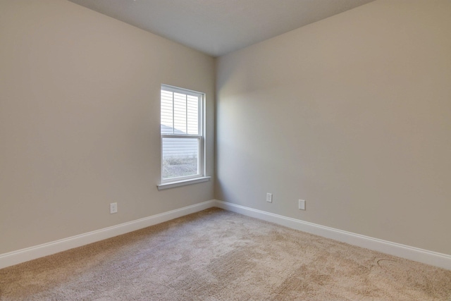 spare room with light carpet and baseboards