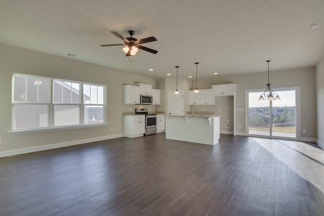 unfurnished living room with ceiling fan, dark wood-type flooring, a sink, visible vents, and baseboards