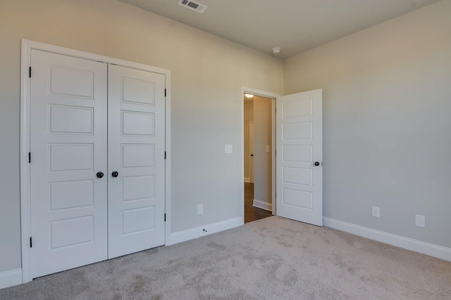 unfurnished bedroom with baseboards, visible vents, a closet, and carpet