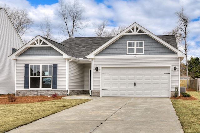 craftsman inspired home featuring driveway, stone siding, fence, and a garage