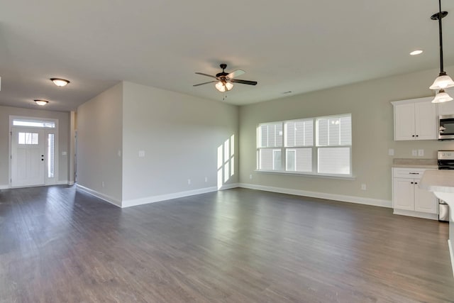 unfurnished living room featuring baseboards, dark wood finished floors, and a ceiling fan