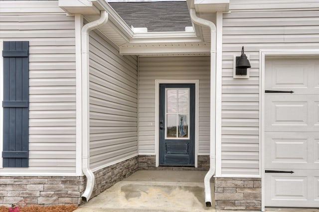 property entrance featuring stone siding, a shingled roof, and a garage