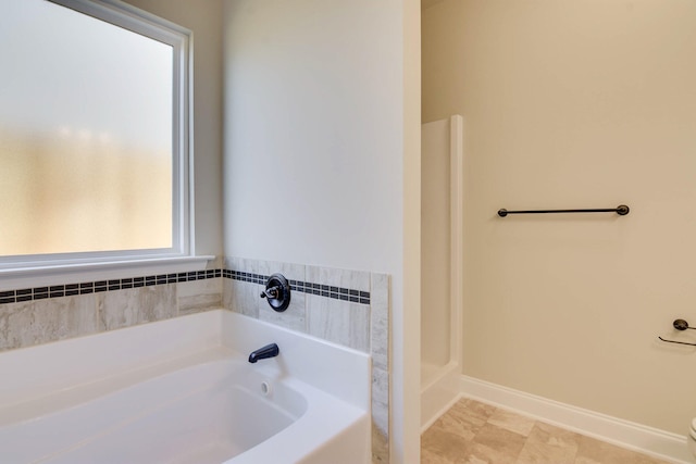 bathroom featuring a bath and baseboards