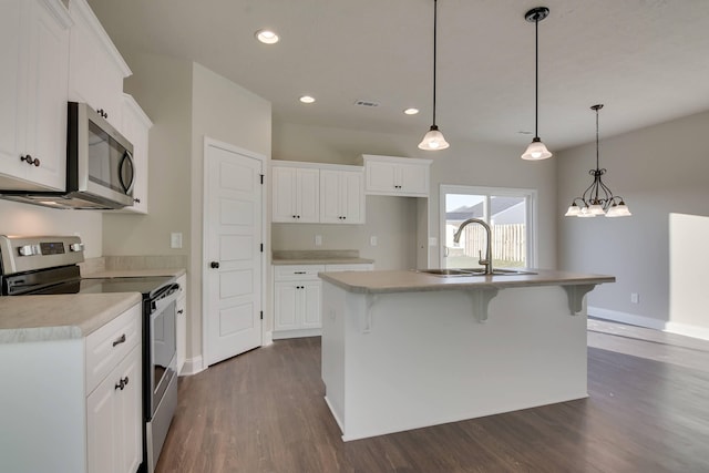 kitchen with dark wood-style floors, stainless steel appliances, visible vents, a kitchen island with sink, and a sink