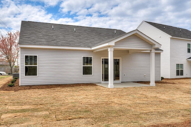 back of property featuring a shingled roof, a patio, and a yard