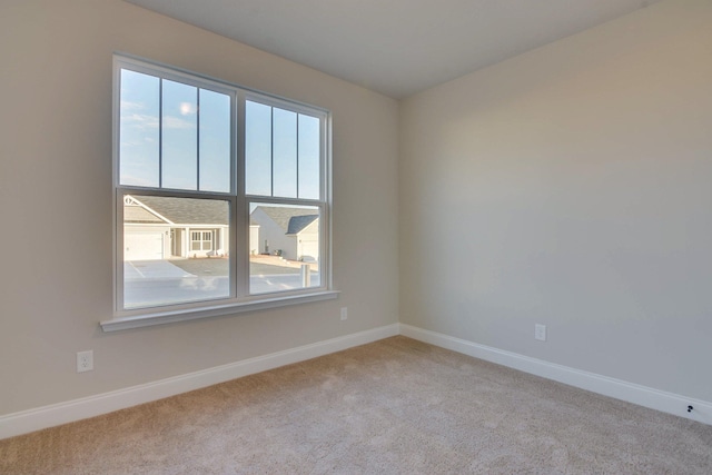 carpeted spare room featuring baseboards