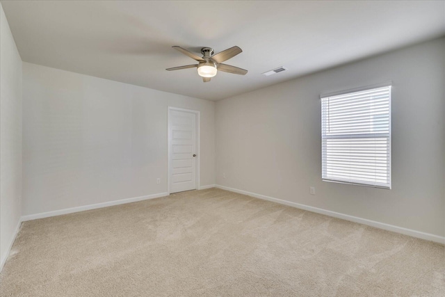 spare room with baseboards, visible vents, ceiling fan, and light colored carpet