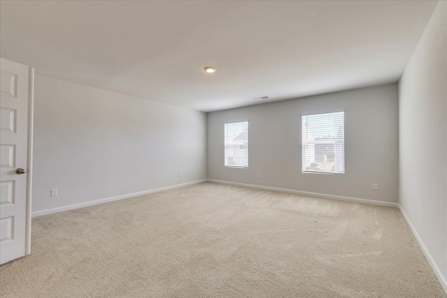 empty room with baseboards, visible vents, and light colored carpet