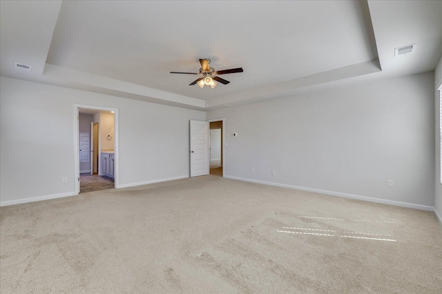 spare room featuring carpet, a raised ceiling, visible vents, and baseboards